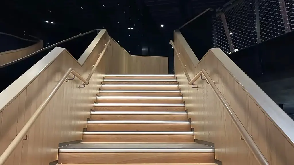 Wide oak panelled staircase at Olympia with LED strip lit treads and brass handrails