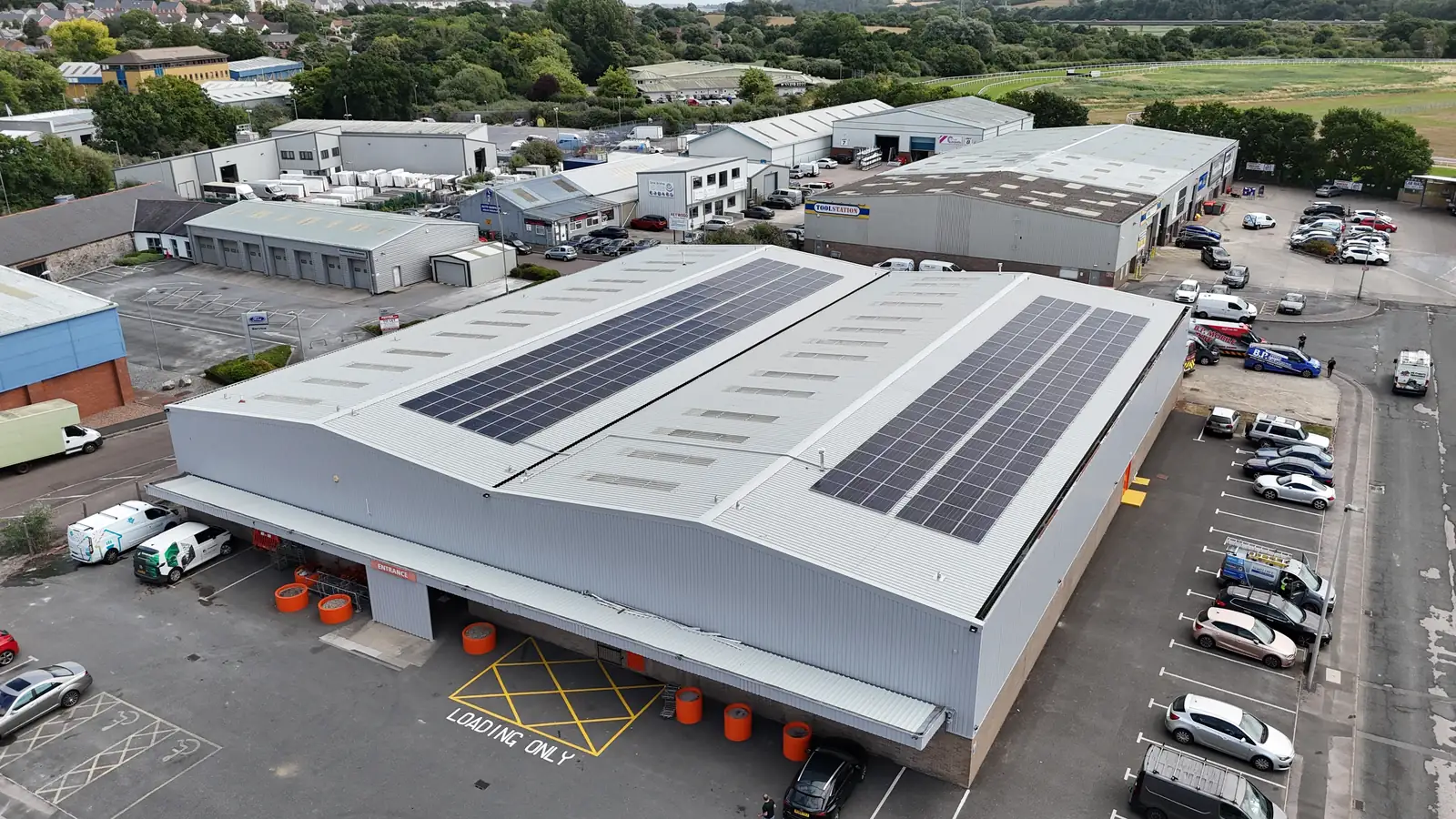 Drone view of two solar arrays across the Booker Newton Abbott warehouse roof and car park