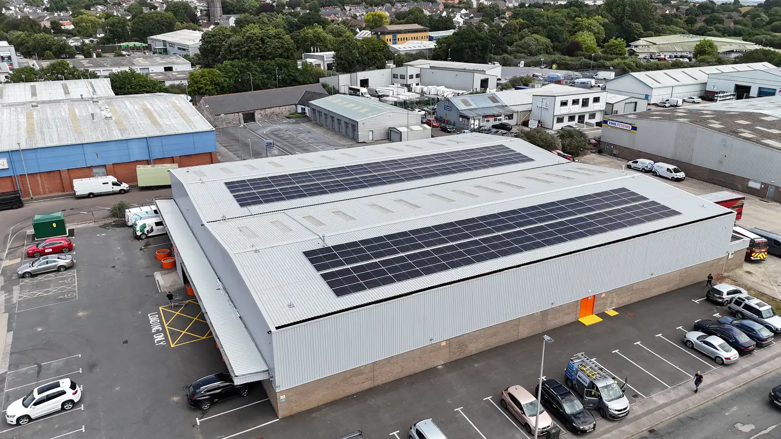 Solar panel rows running along the pitched roof of the Booker Newton Abbott warehouse