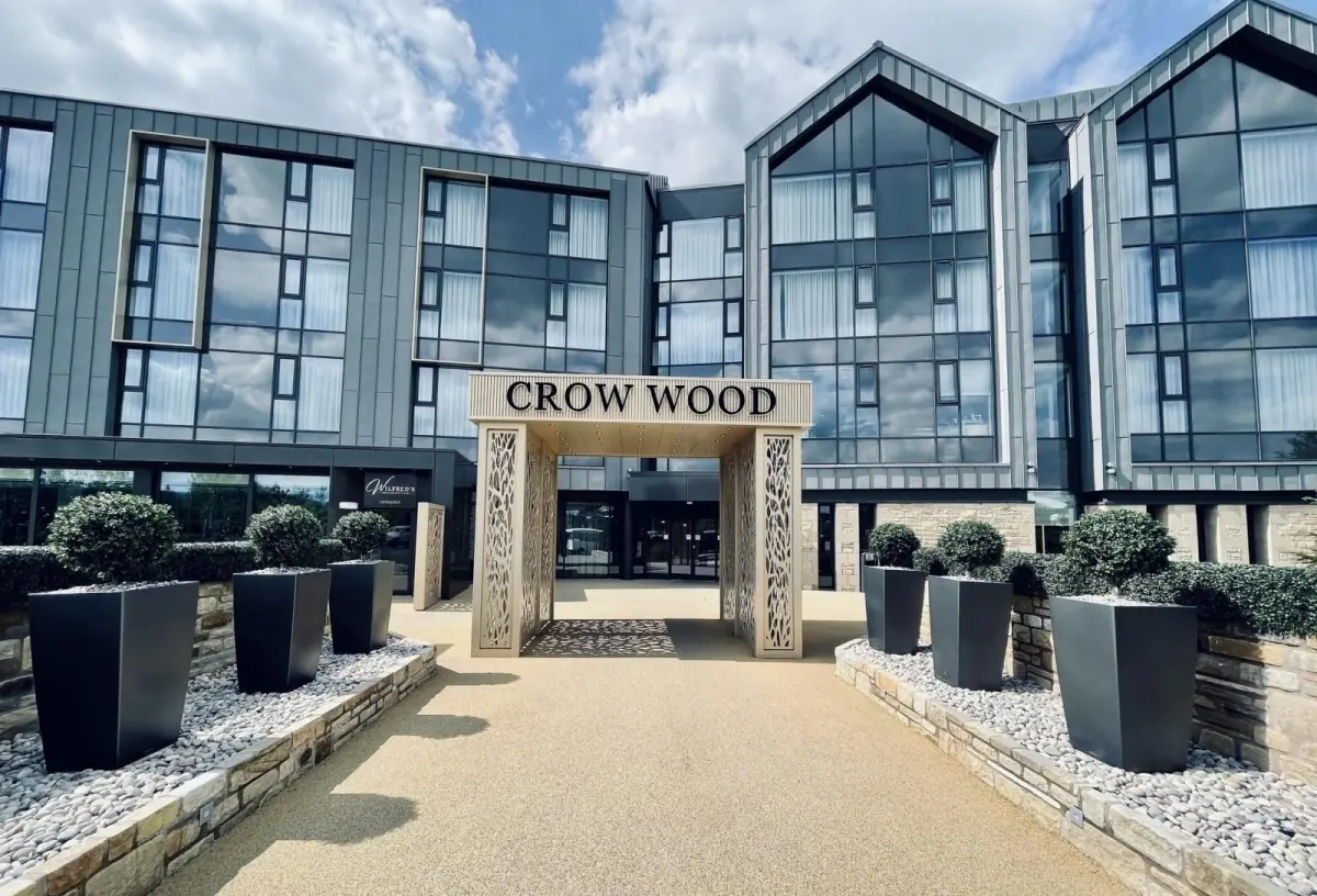 Crow Wood hotel entrance with stone portal sign, zinc clad gables and clipped topiary planters