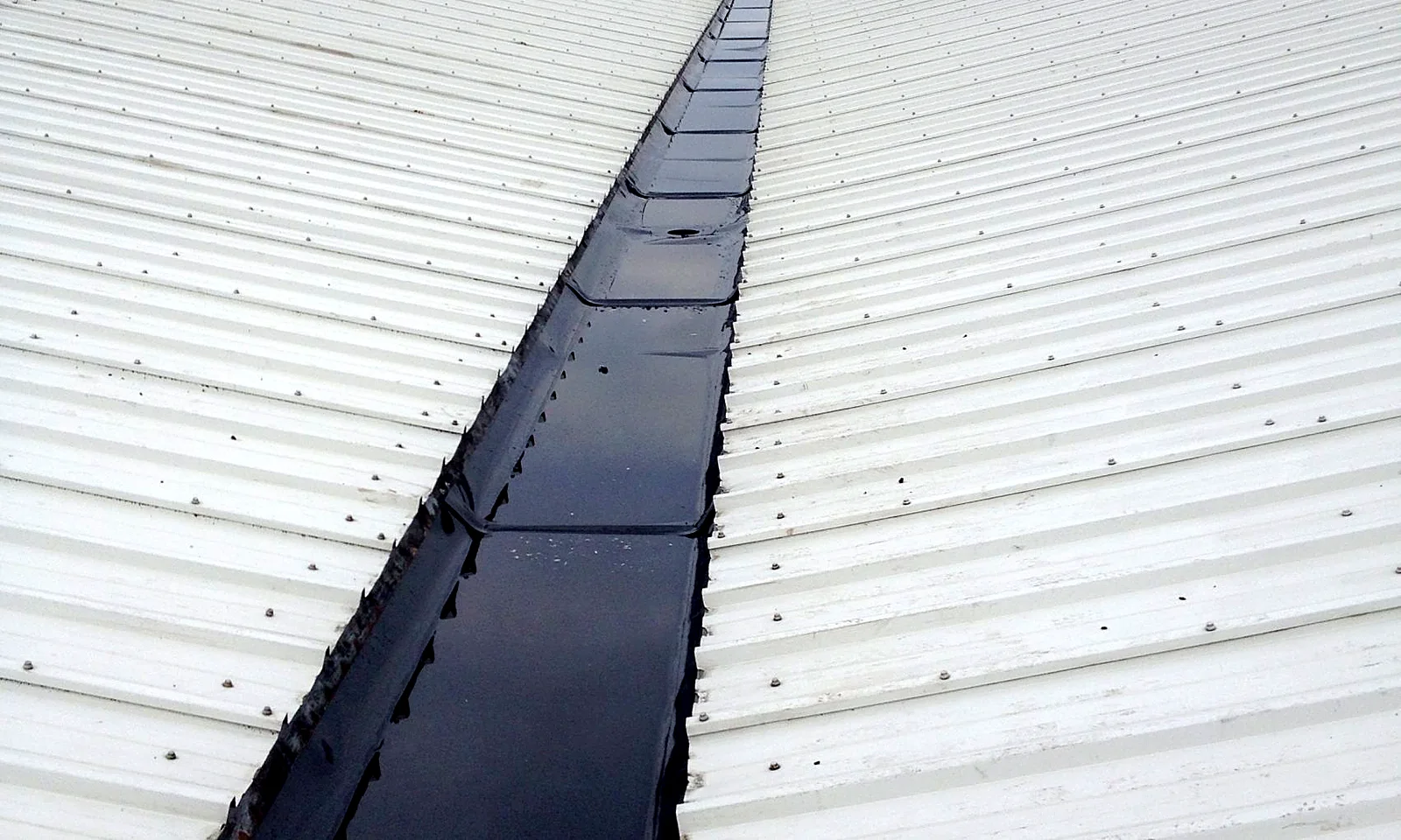 Lined valley gutter between two white metal roof slopes at Halewood International