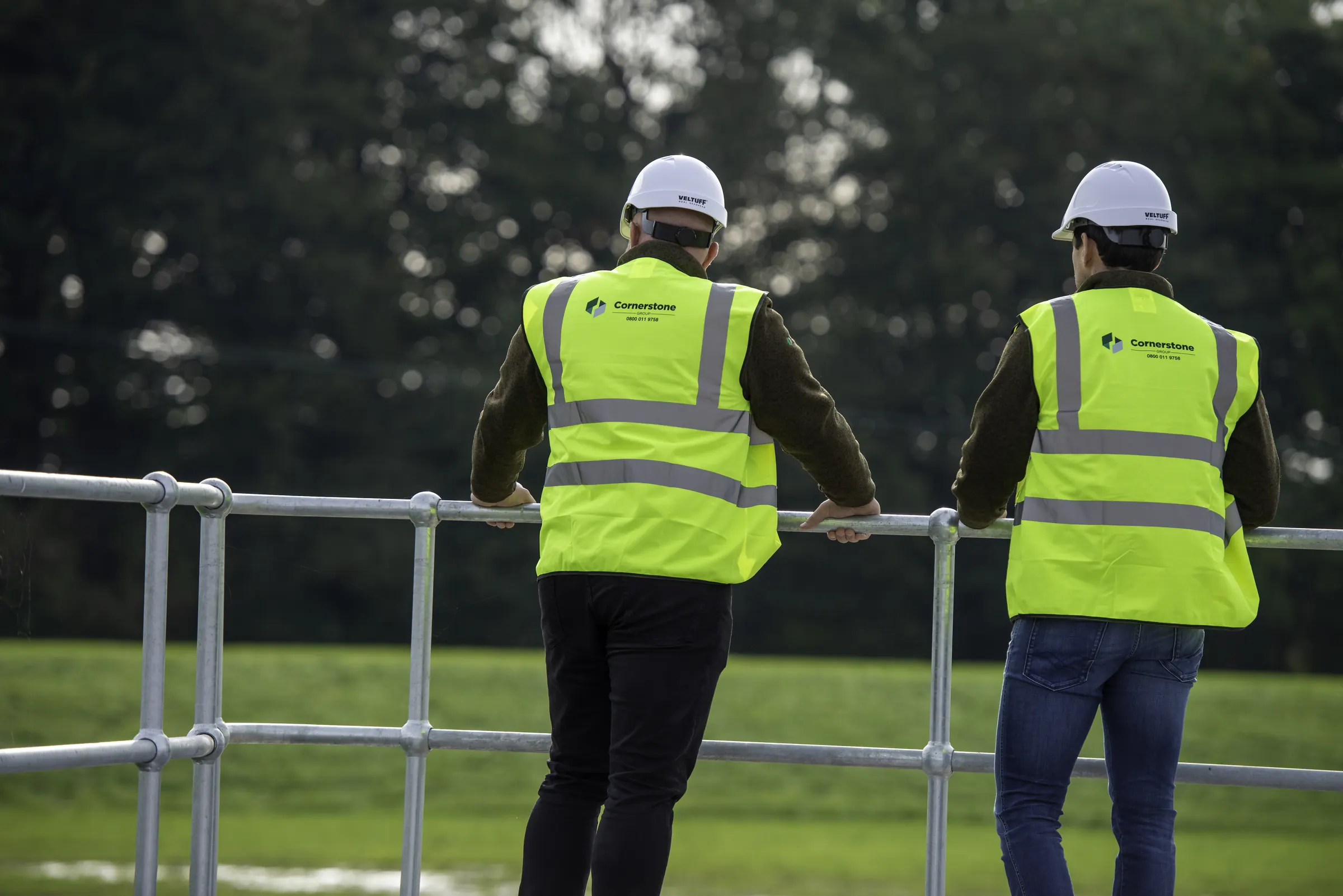 Cornerstone staff in hard hats and branded hi-vis overlooking a utilities site