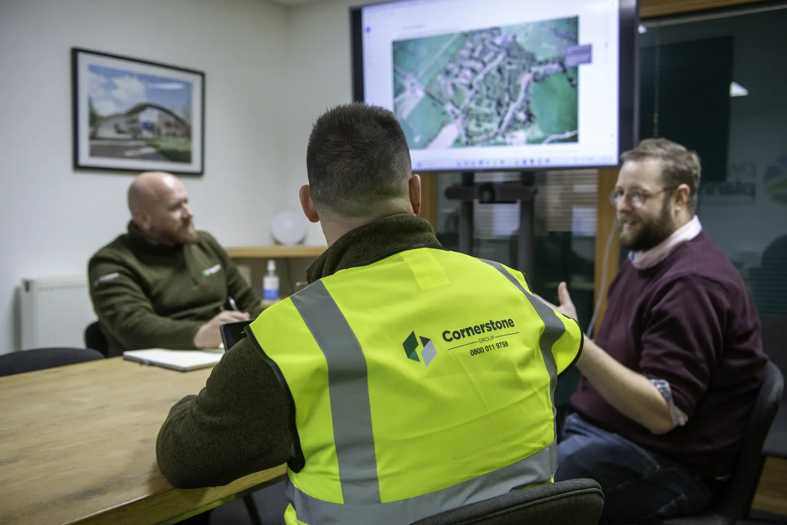 Cornerstone staff in branded hi-vis and fleeces discussing a project in a meeting room