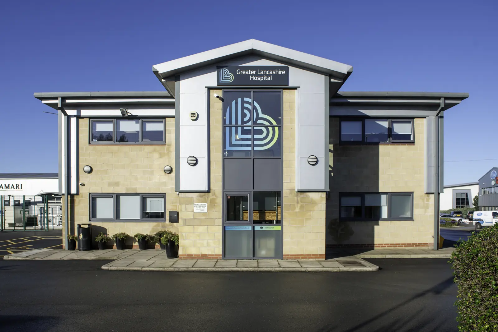 Front elevation of Greater Lancashire Hospital with buff brick, grey cladding and blue sky
