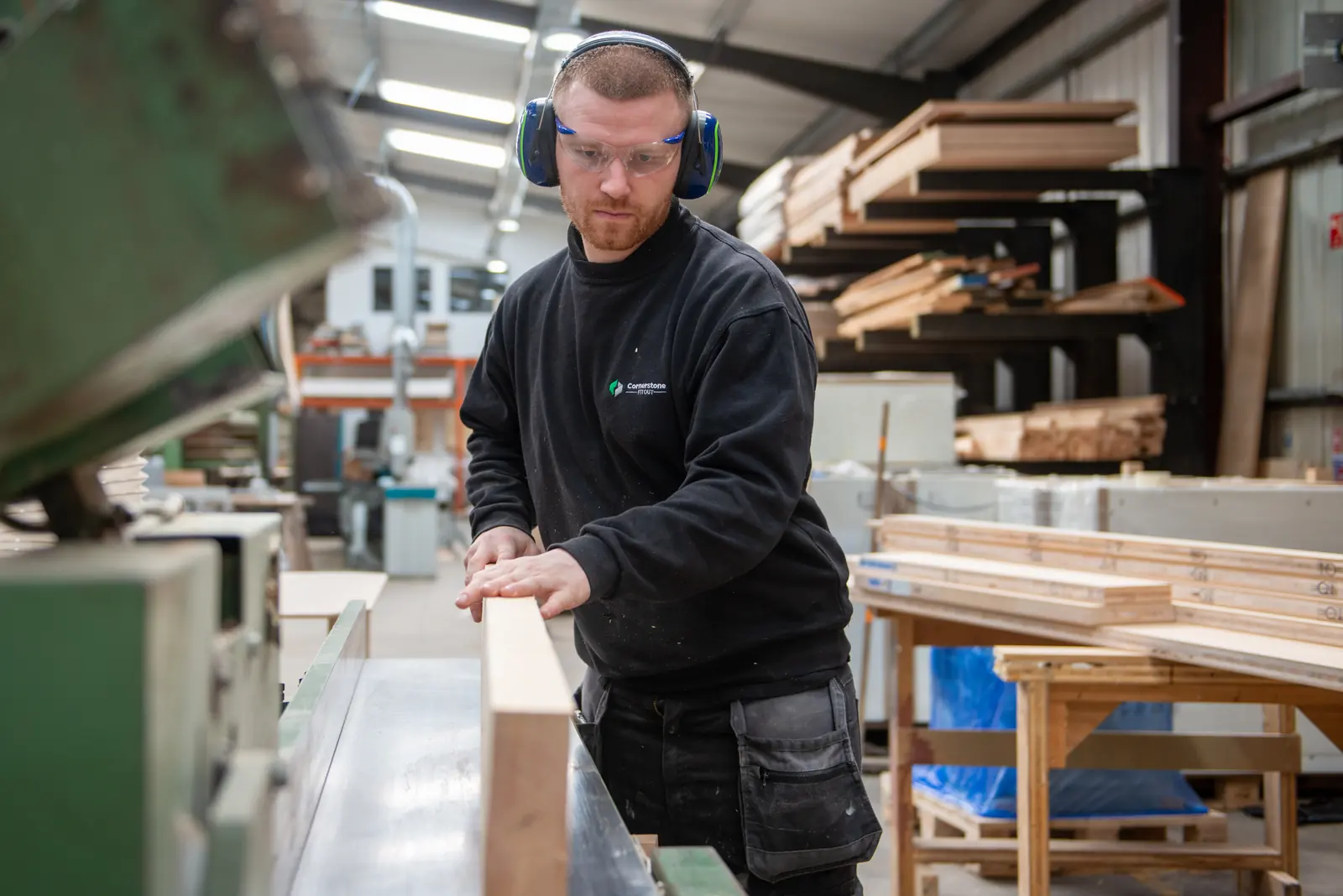 Cornerstone joiner in ear defenders and safety glasses feeding timber through a planer