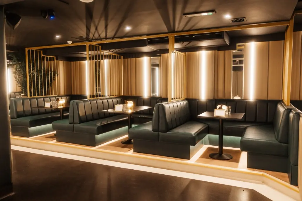 Baluga bar interior with dark green leather booths, timber slatted walls and warm uplighting