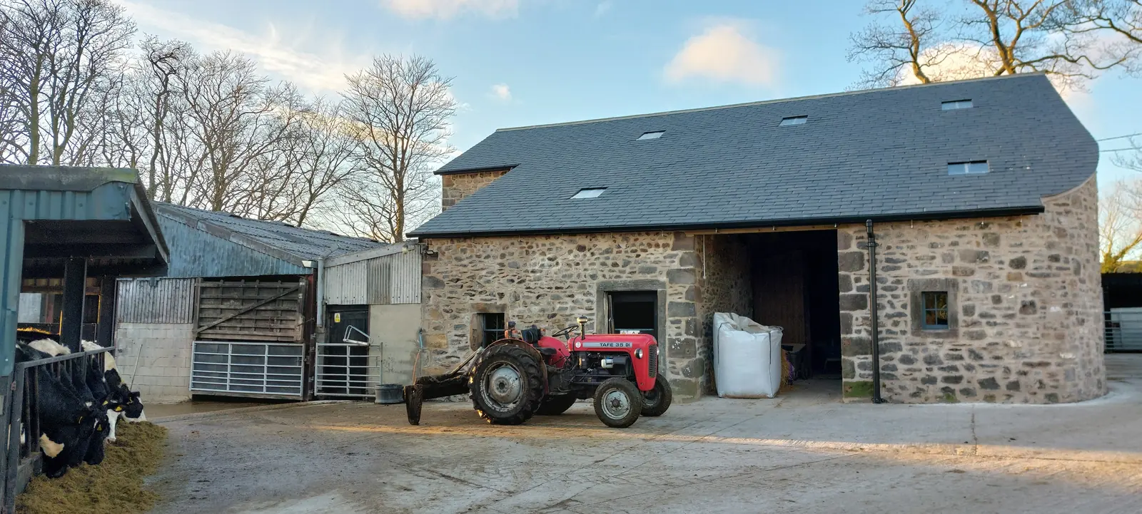 Restored stone barn at Fober Farm with new slate roof on a sunny day