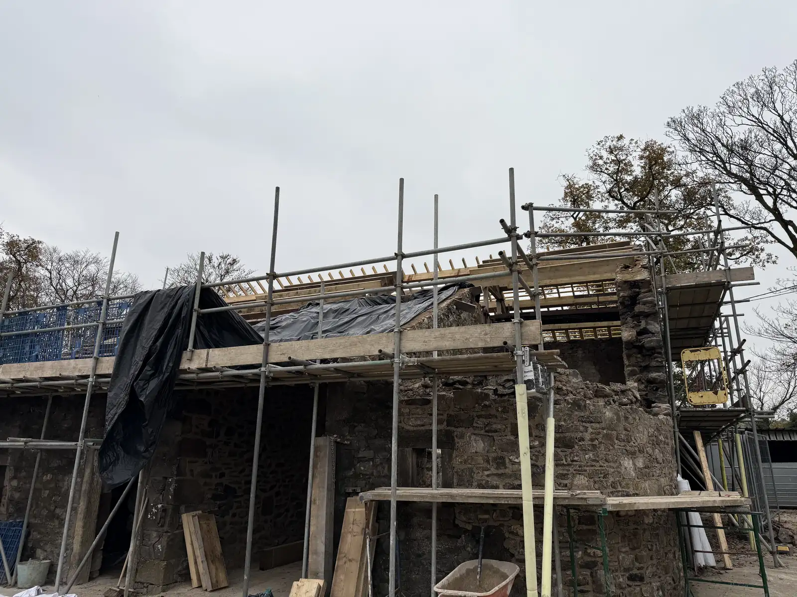 Barn gable with scaffolding and the old roof being stripped back