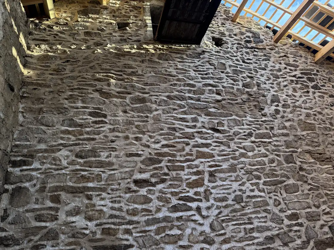 Interior stone wall of a barn at Fober Farm freshly repointed in lime mortar