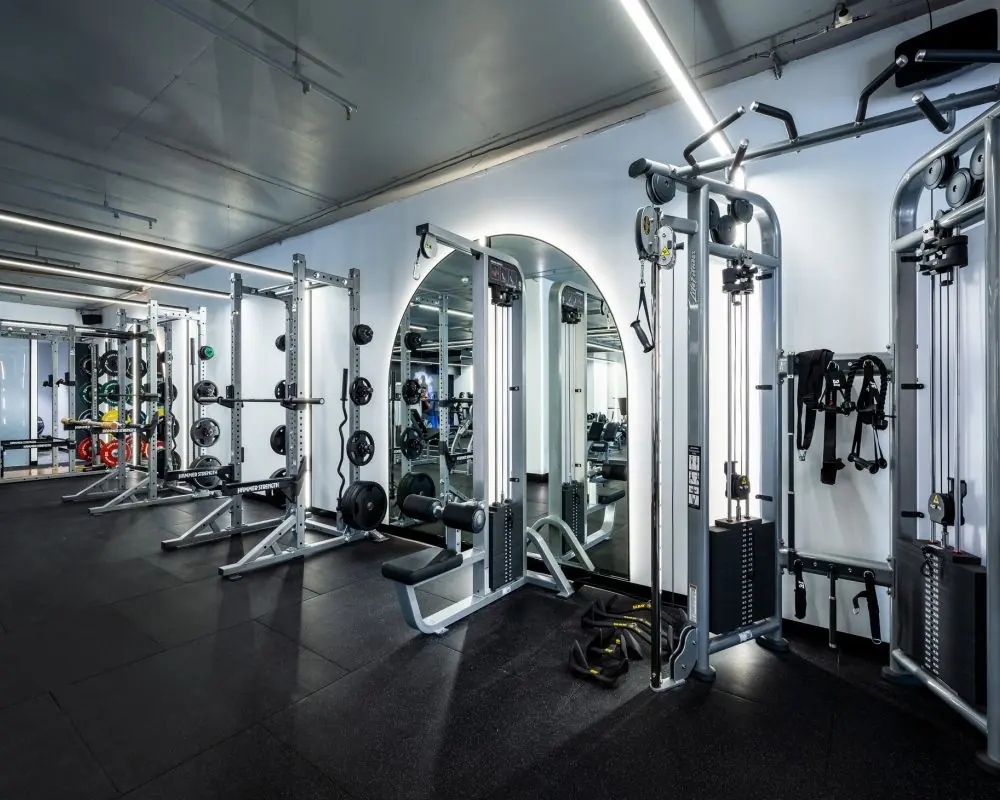 Gym fit-out showing cable machines and arched mirrors against white walls