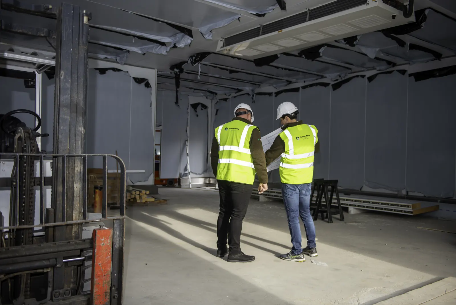 Cornerstone team in hard hats and hi-vis inspecting an insulated panel interior with drawings