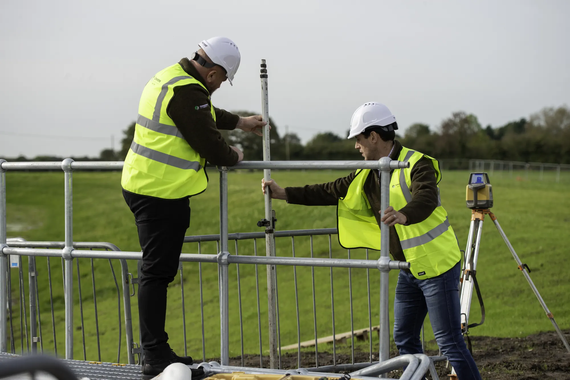 Cornerstone engineers in hard hats and hi-vis setting out with a levelling staff and laser