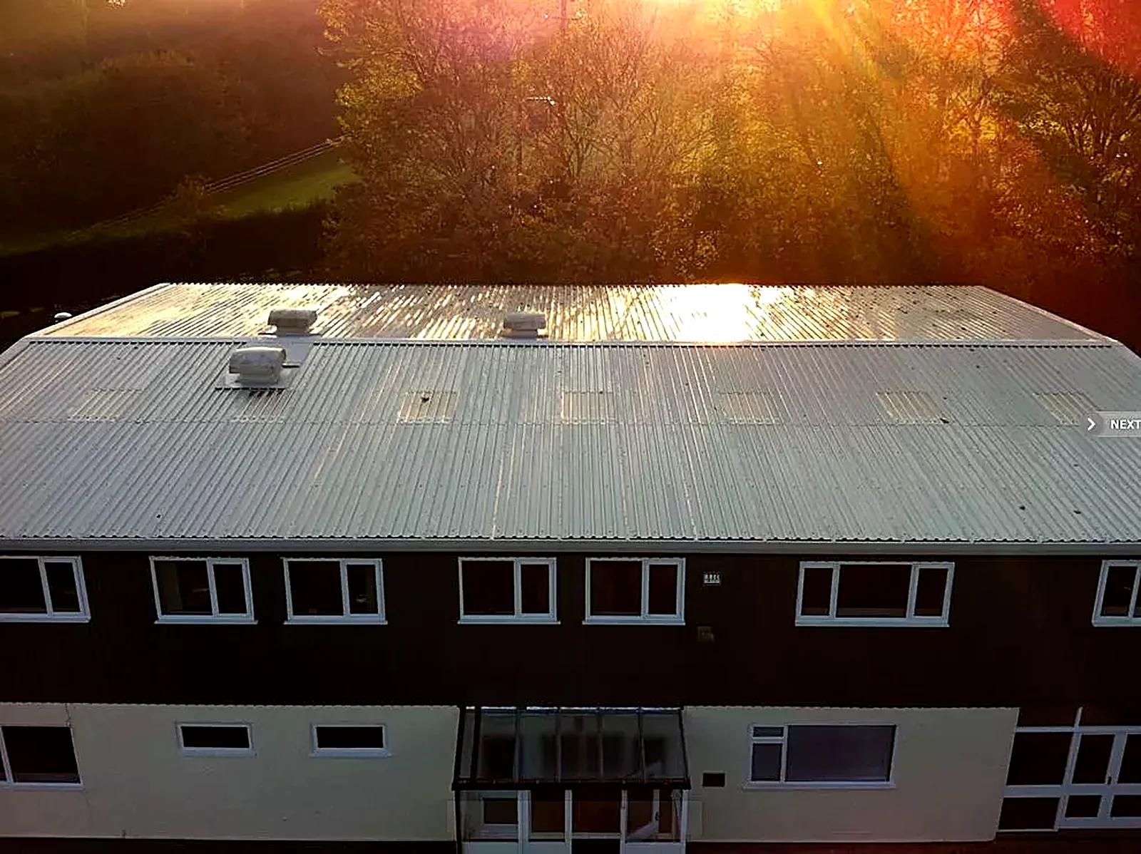 Office building with its new twin-skin insulated metal roof in evening sun